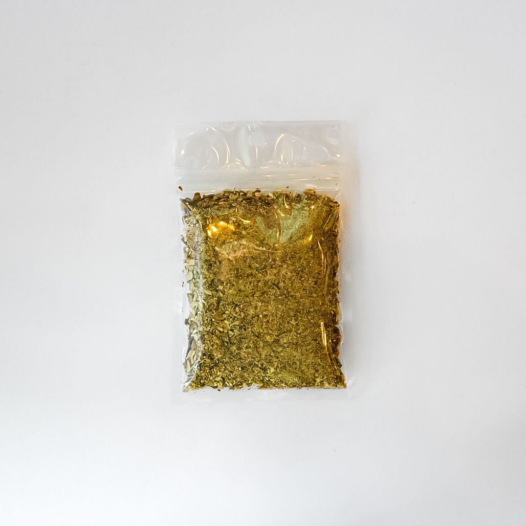 Small clear plastic bag of dried herbs with a bright yellow label on a white background