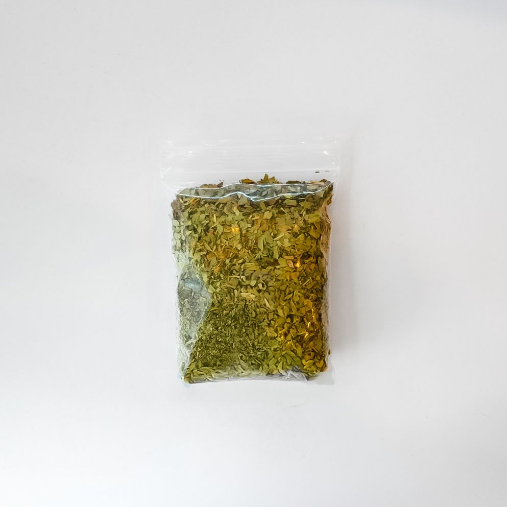 Small clear plastic bag of dried herbs with a bright yellow label on a white background