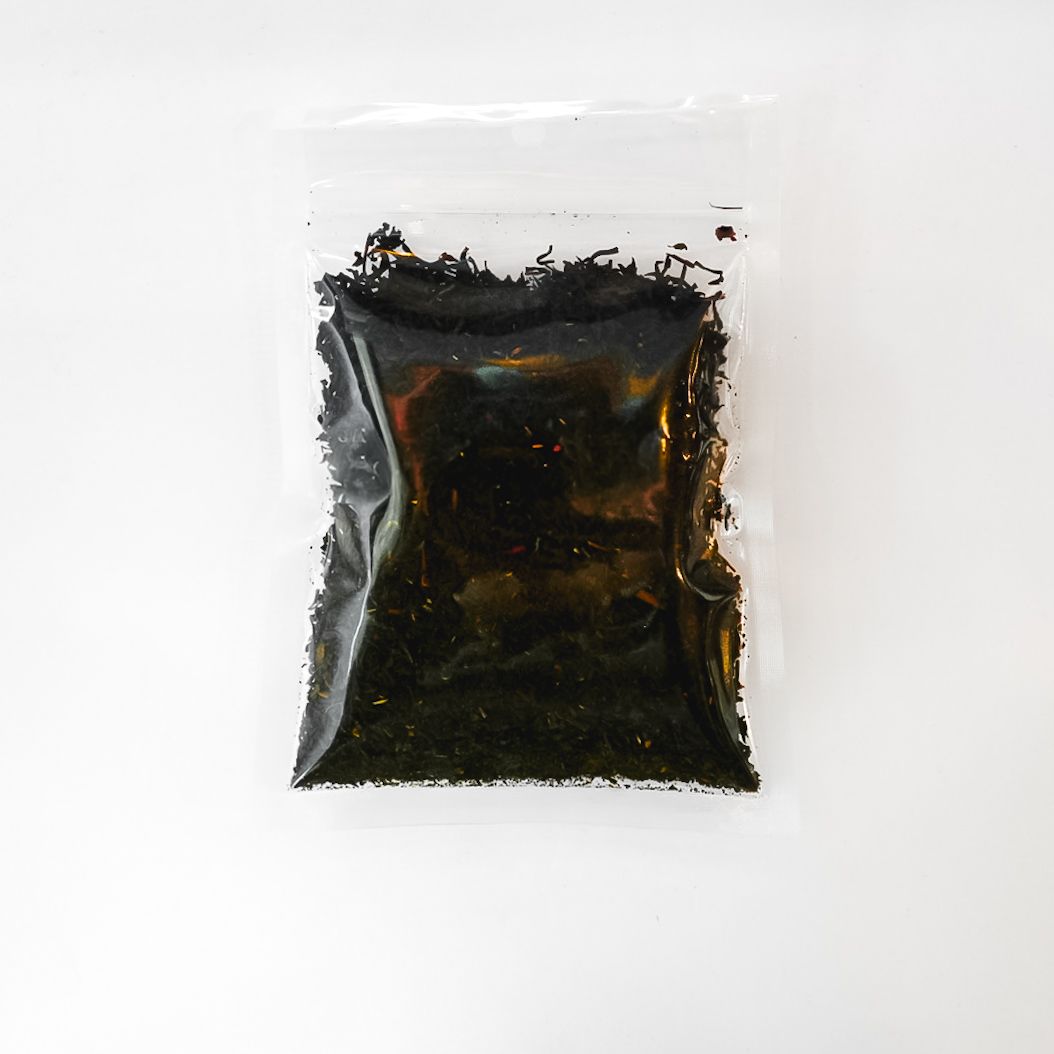 Clear plastic bag of Earl Grey tea leaves with a yellow label on a white background