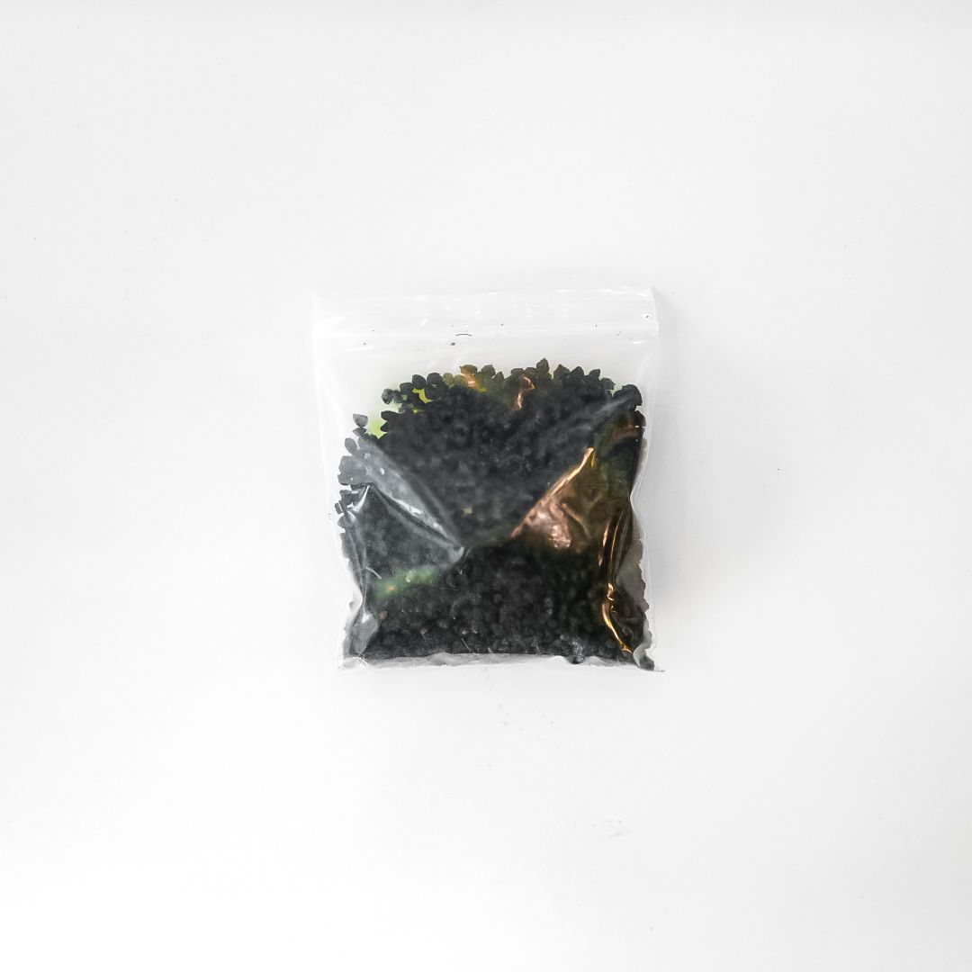 Small clear bag of dark green dried herbs with a bright yellow label on a white background