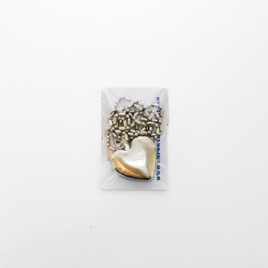 Small clear packet of shiny silver pieces with a gold heart-shaped charm on a white background