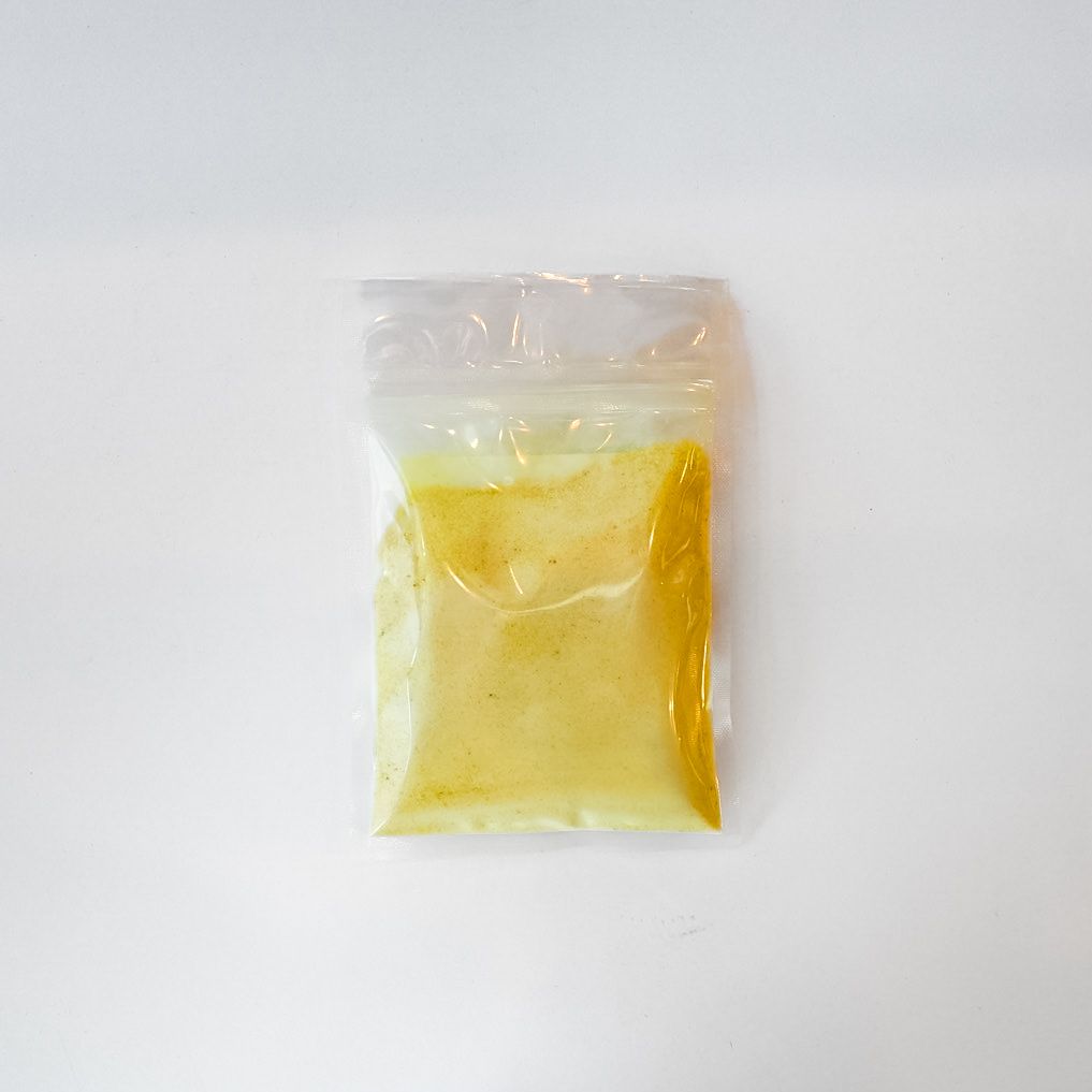 Small clear plastic packet with yellow powder and a bright yellow label on a white background