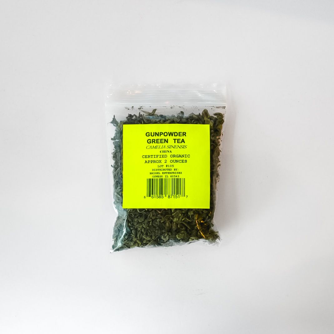 Small clear plastic bag of dried green herbs with a bright yellow label on a white background