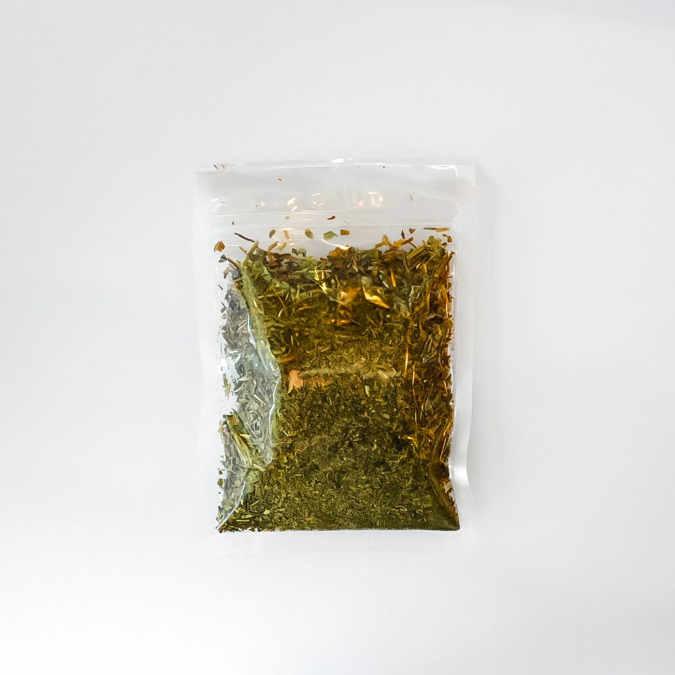 Clear plastic bag of dried herbs with a bright yellow label on a white background