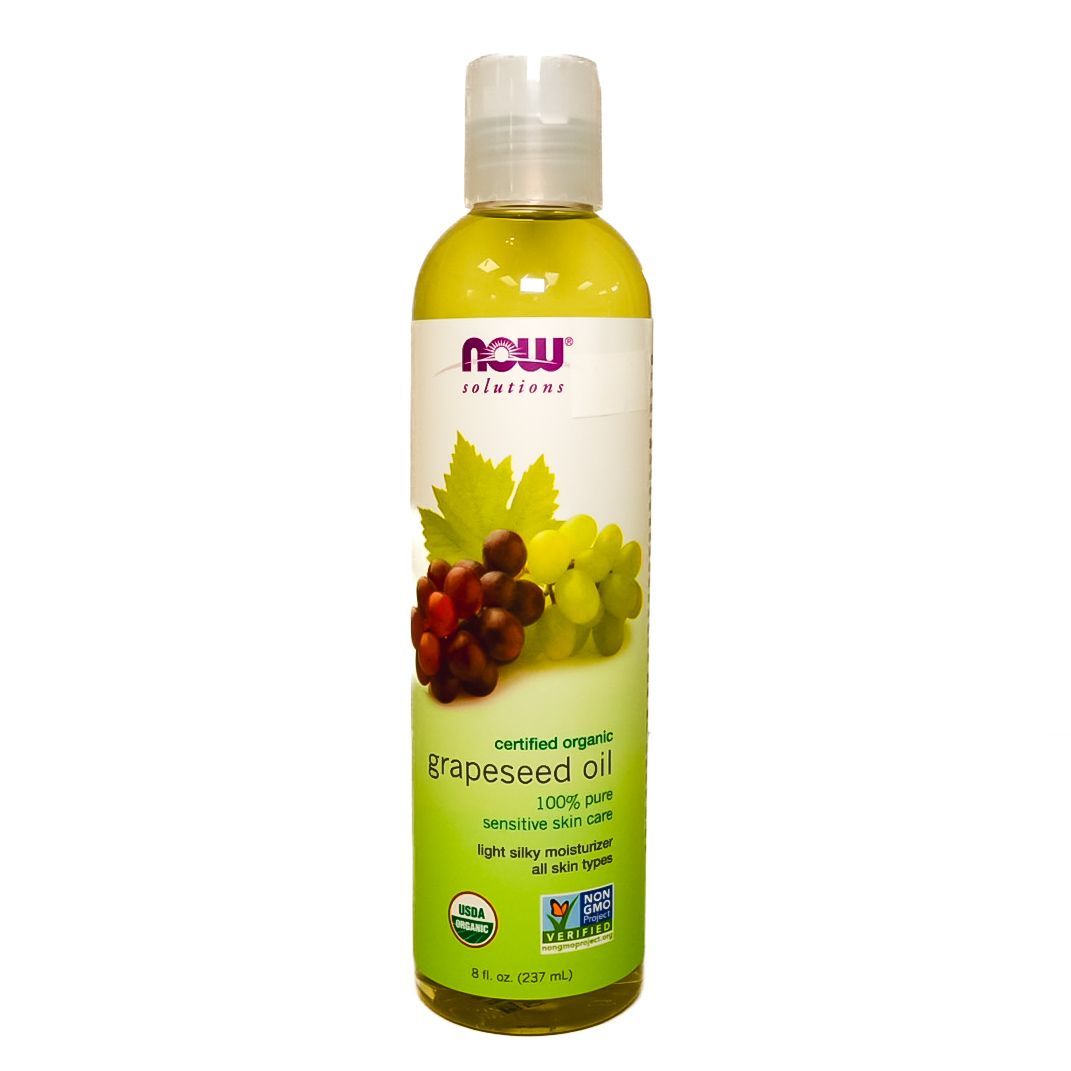 Bottle of yellow-green grapeseed oil with grapes and leaf label, standing on a white background