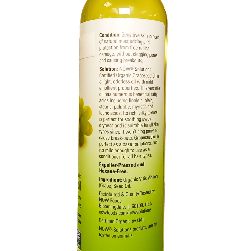 Bottle of yellow-green grapeseed oil with grapes and leaf label, standing on a white background