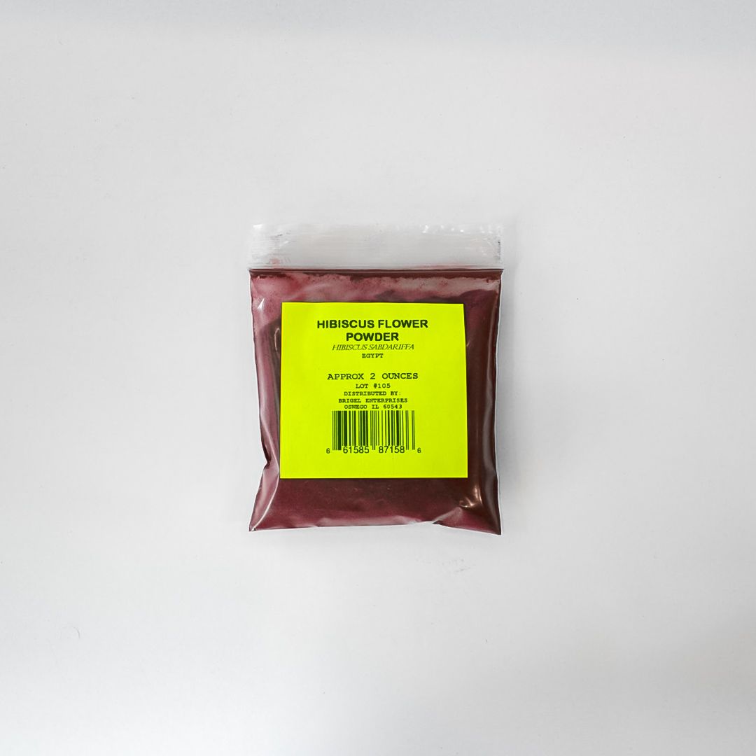 Clear plastic bag of maroon powder with a bright yellow label on a white background