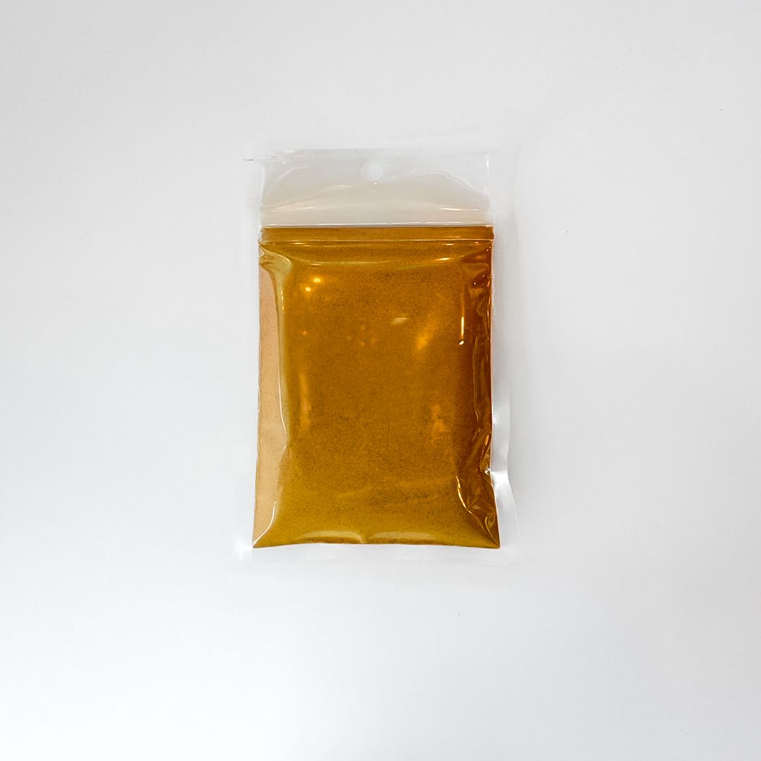 Small clear plastic packet of amber powder with a bright yellow label on a white background
