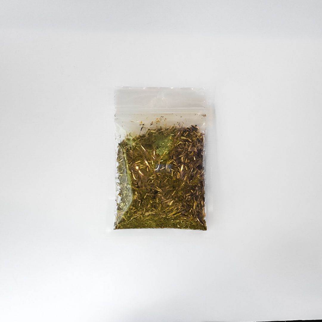 Clear plastic bag of dried herbs with a bright yellow label on a white background