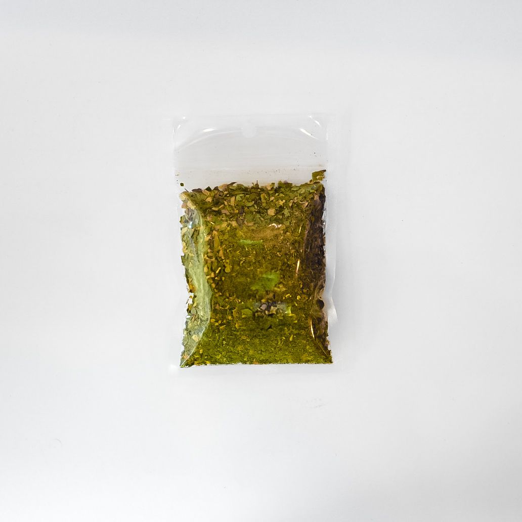 Small clear plastic bag of dried herbs with a bright yellow label on a white background