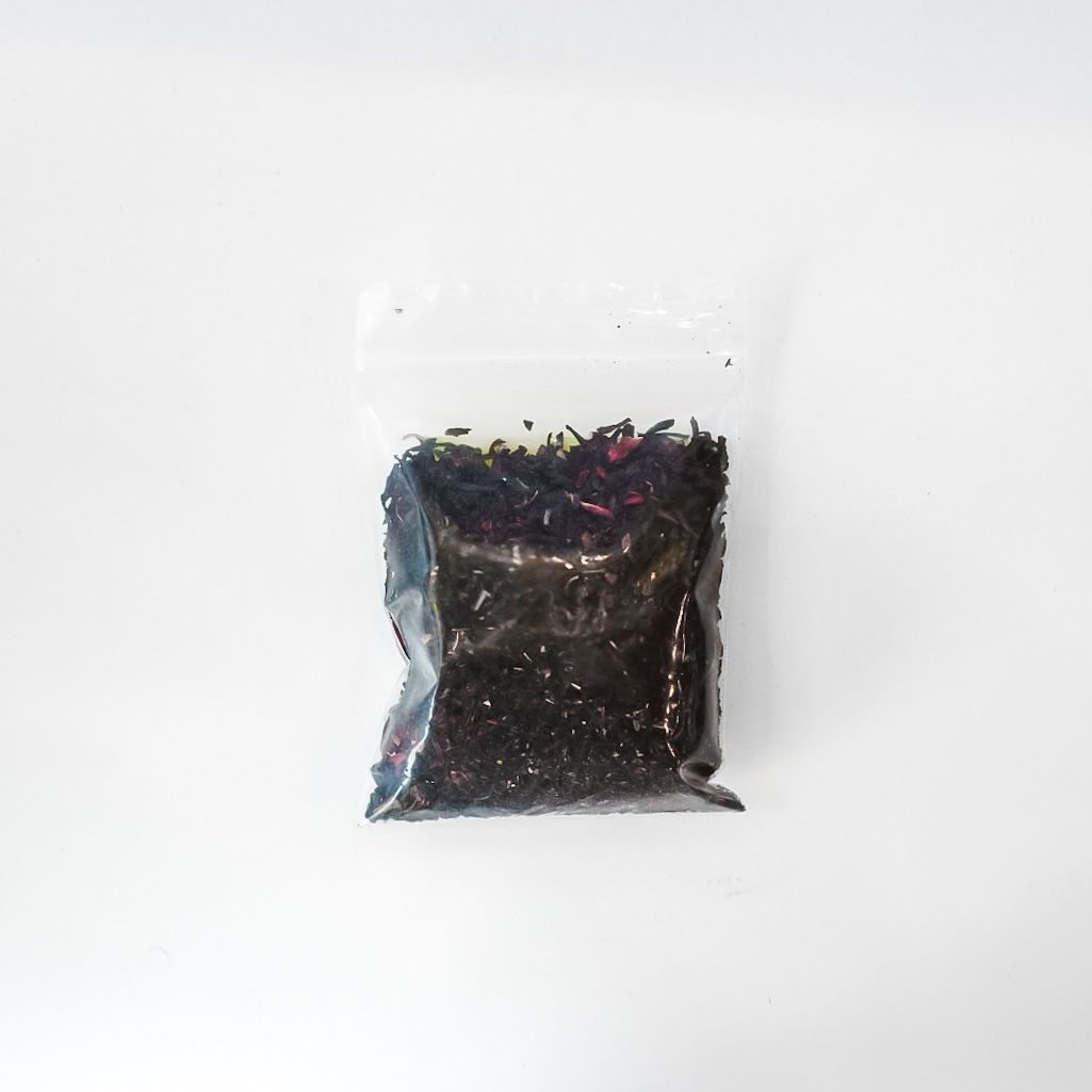 Small clear bag of dried hibiscus flowers with a bright yellow label on a white background