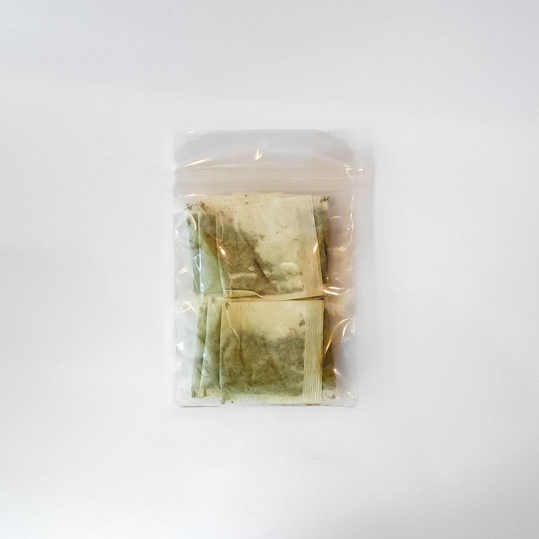 Clear plastic bag of loose herbal tea with a bright yellow label on a white background
