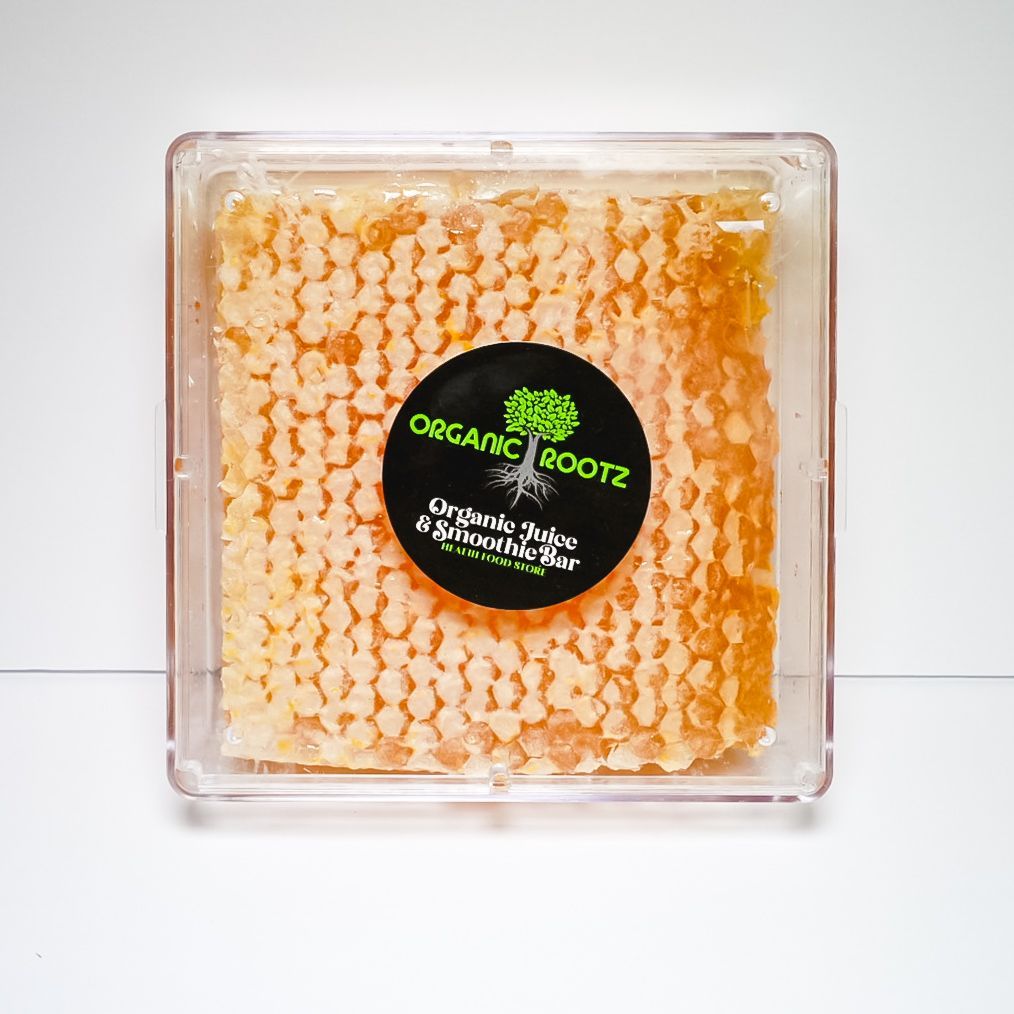 Clear square container of orange organic roots with a black-and-green label on a white background