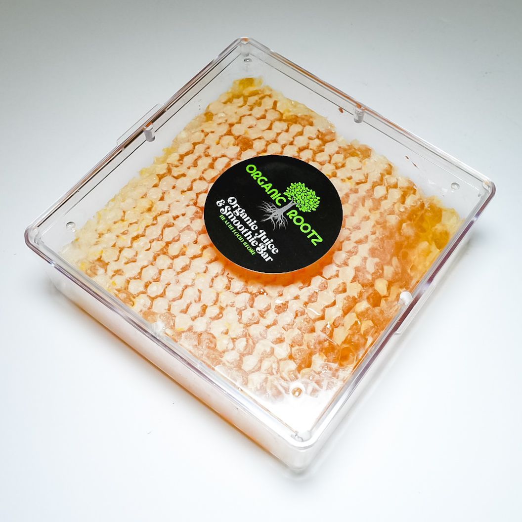 Clear square container of orange organic roots with a black-and-green label on a white background