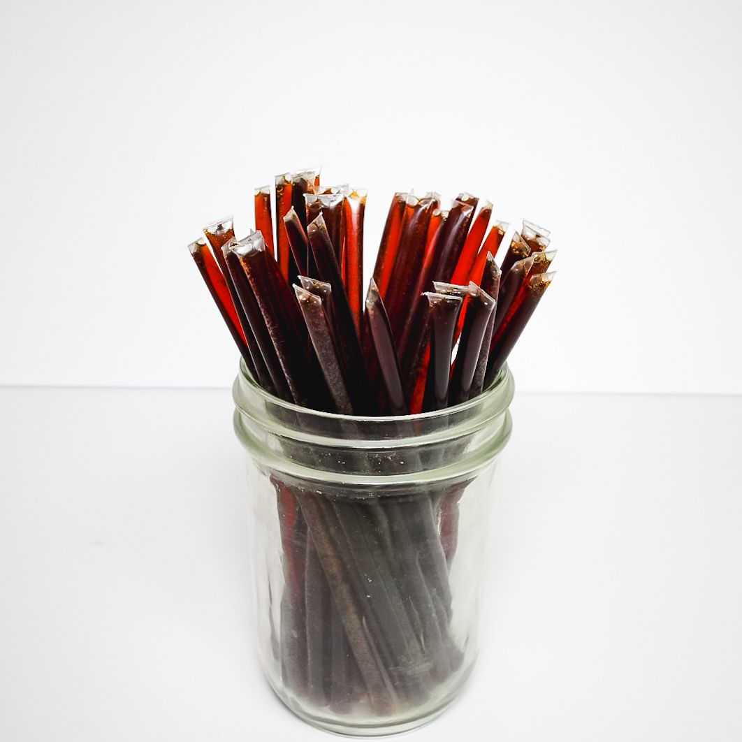 Jar filled with red and black pencils against a white background