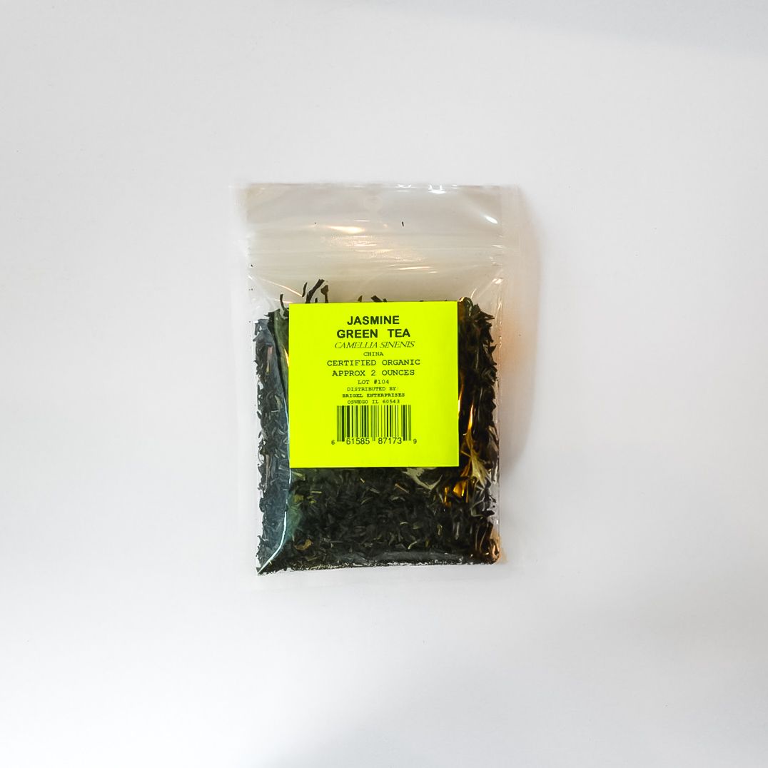 Small clear plastic bag of dark loose tea with a bright yellow label on a white background