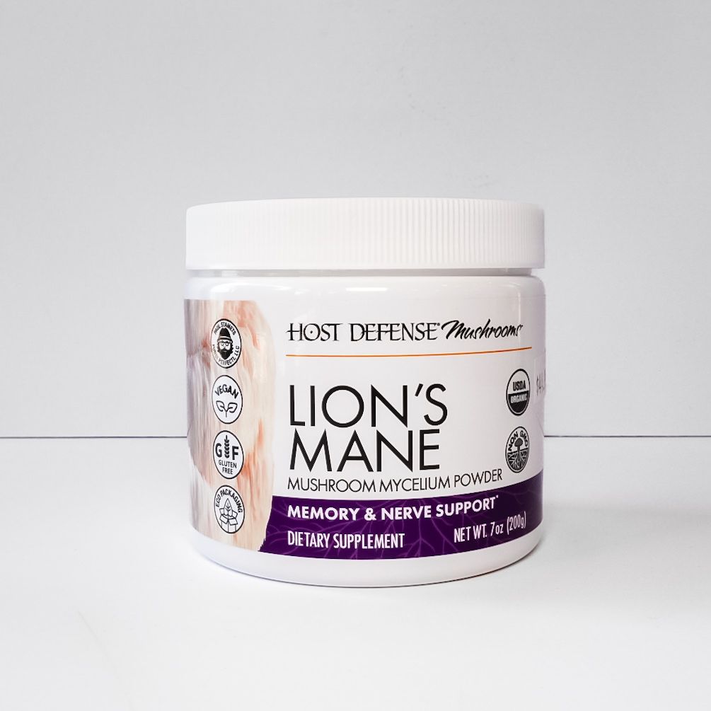 White jar of Host Defense Lion’s Mane mushroom supplement with purple label on a light background