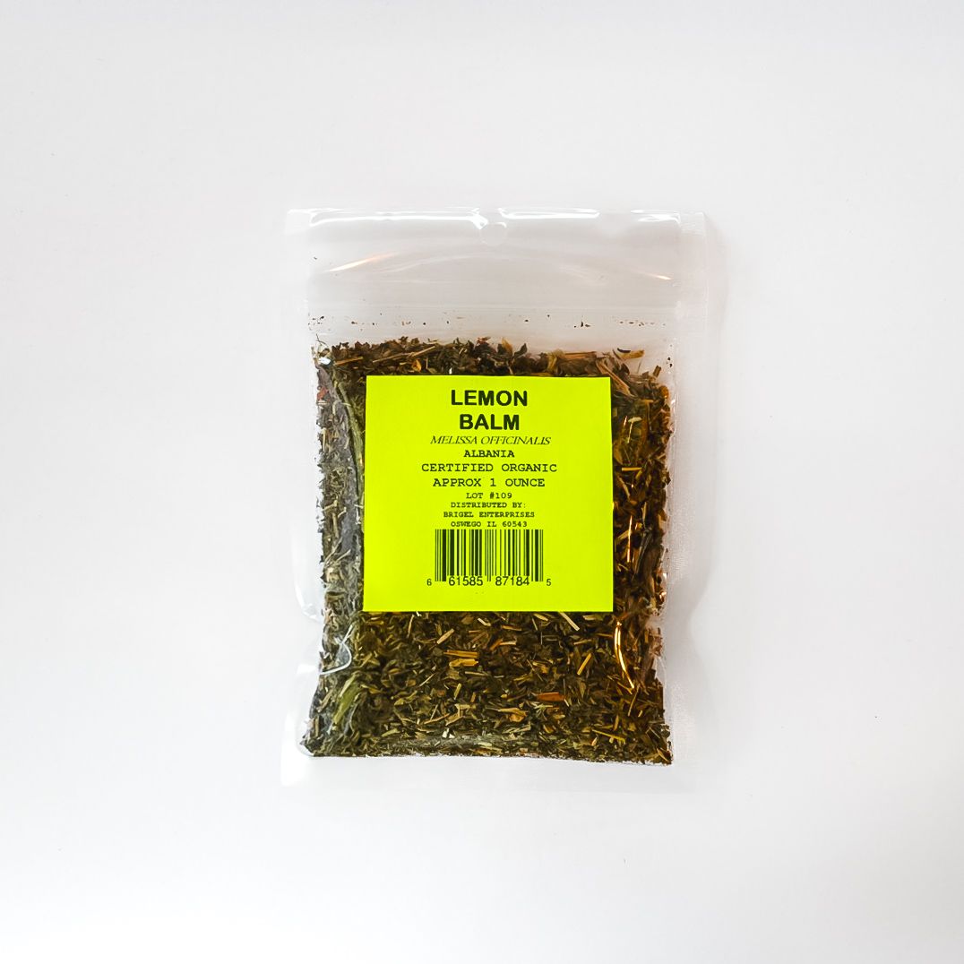 Clear plastic bag of dried lemon balm with a bright yellow label on a white background