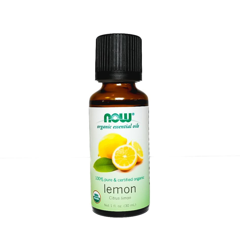 Small amber bottle of NOW essential oil with lemon label and sliced lemon on white background