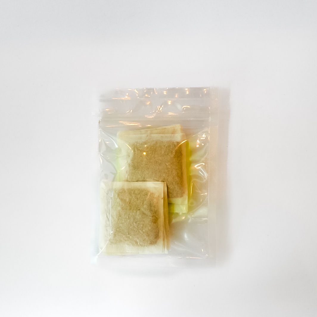 Clear plastic bag of dried lemongrass tea bags with a bright yellow label on a white background