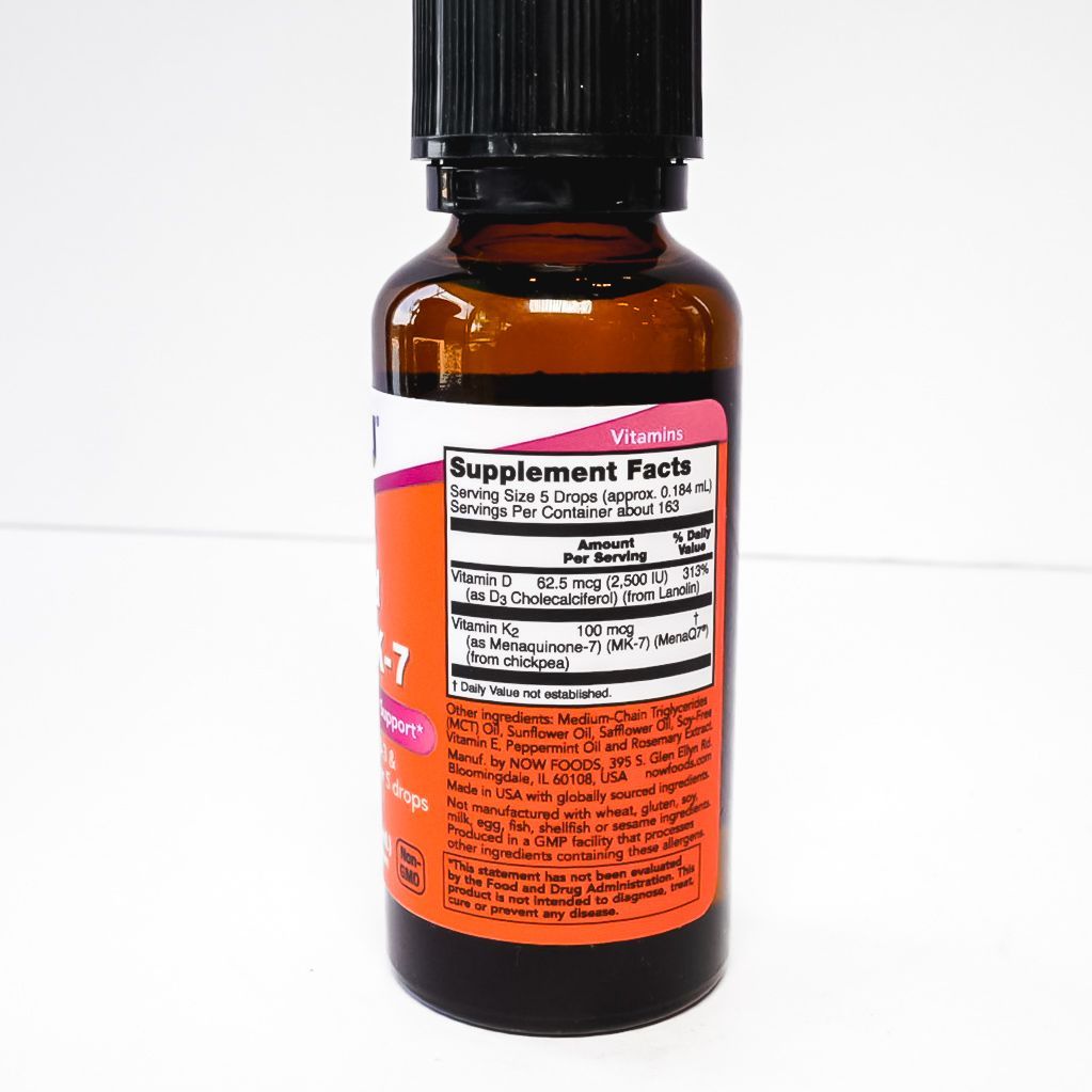 Small amber supplement bottle with black cap and orange label on a white background