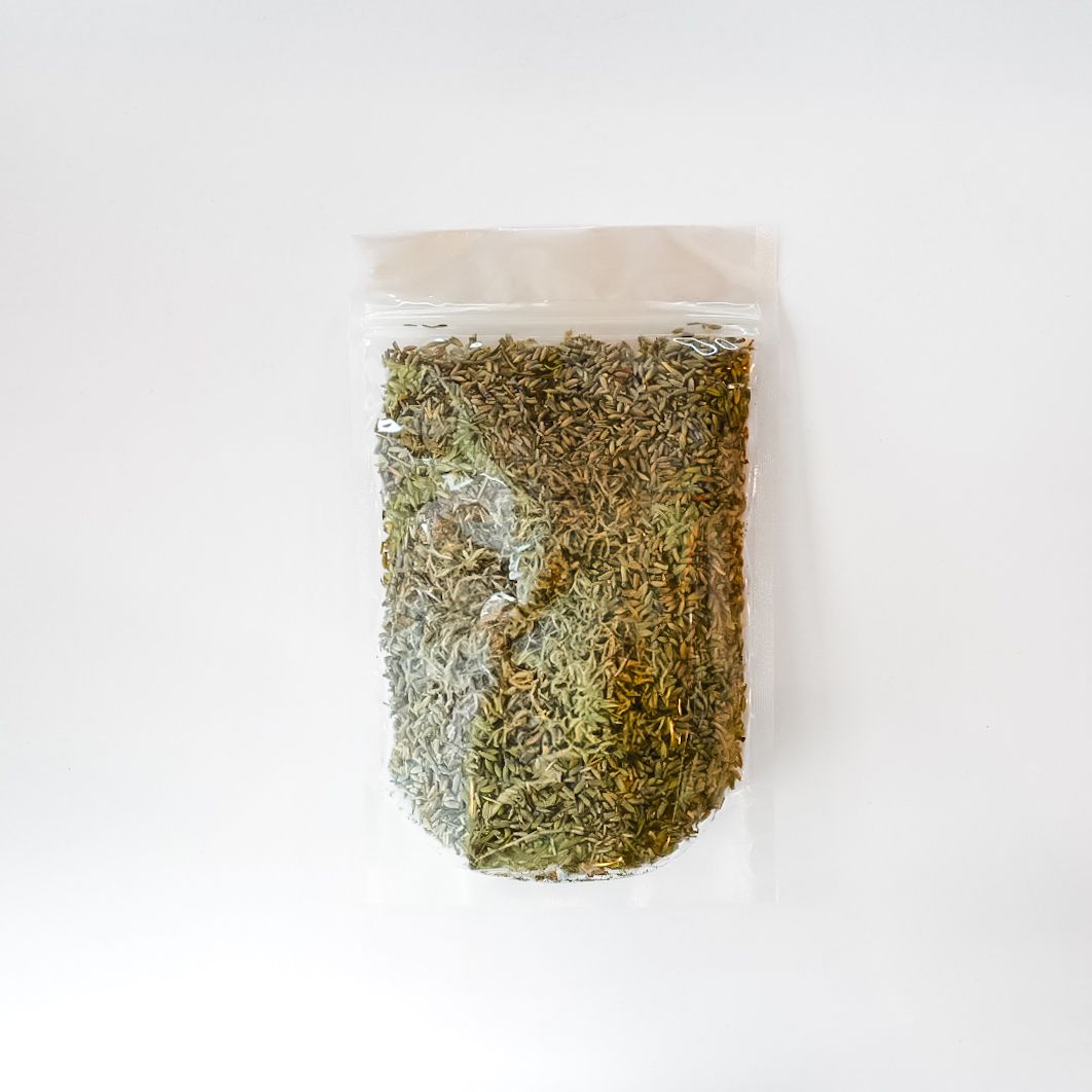 Clear plastic bag of dried herbs with a bright yellow label on a white background
