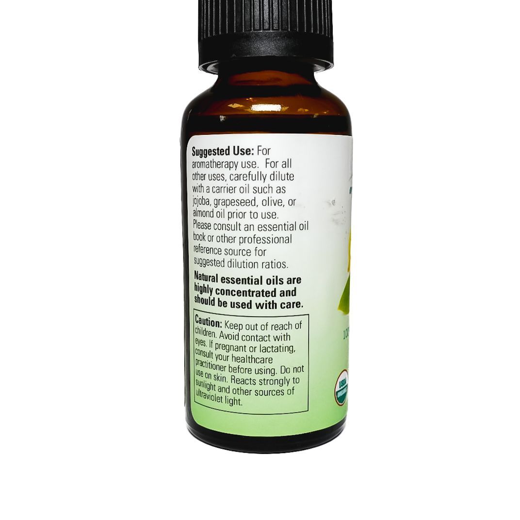 Small amber bottle of NOW essential oil with lemon label and sliced lemon on white background