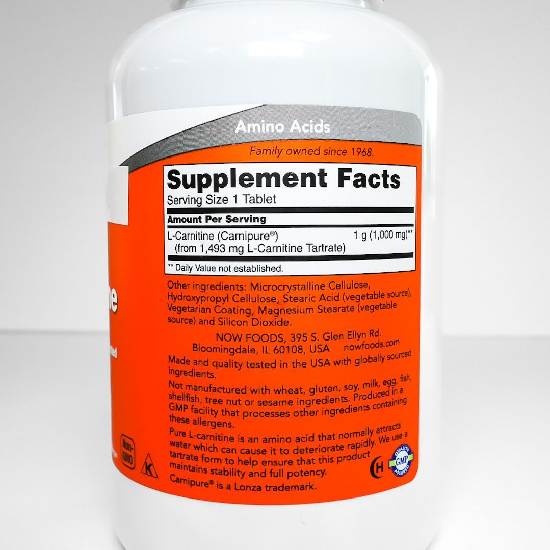 Bottle of L-carnitine supplement with white label and orange front, purple cap on white background