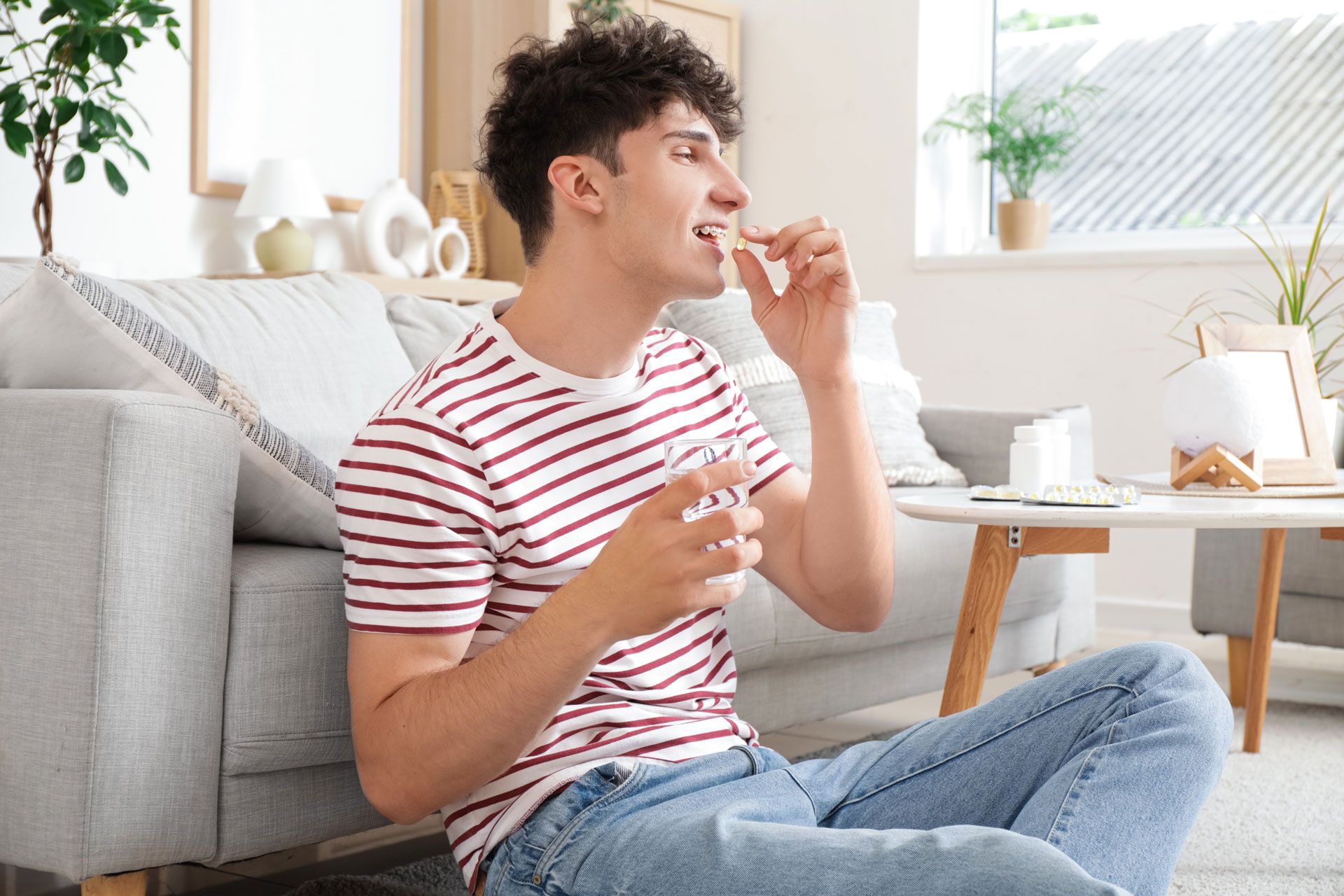 Person sitting on a couch, eating a snack in a bright living room.