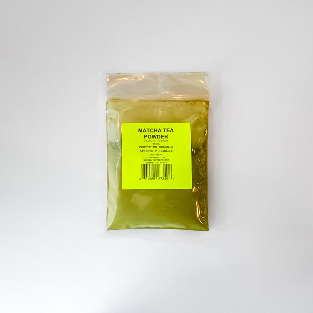 Small clear plastic bag with yellow label and green powder inside on a white background