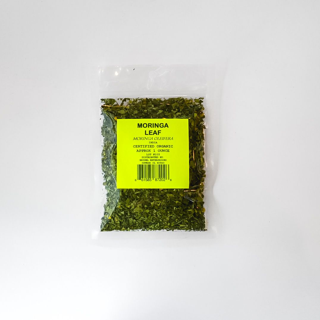 Small clear bag of green herbal material with a bright yellow label on a white background