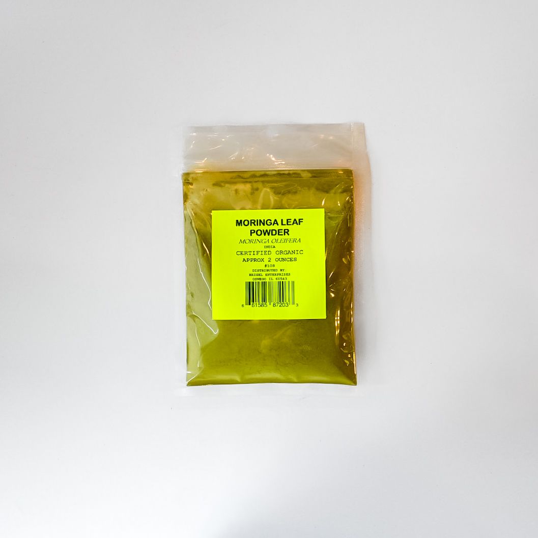 Small clear plastic pouch with yellow label containing greenish powder on a white background
