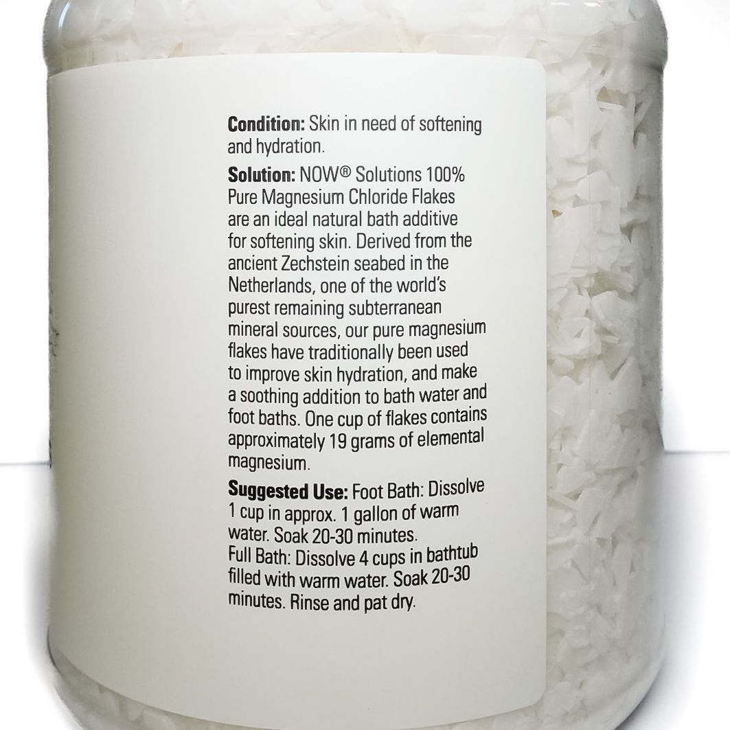 Jar of NOW Solutions magnesium flakes with white lid and label on a plain background