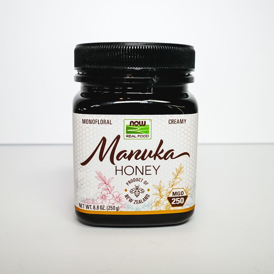 Manuka honey jar with black lid and white label on a light background