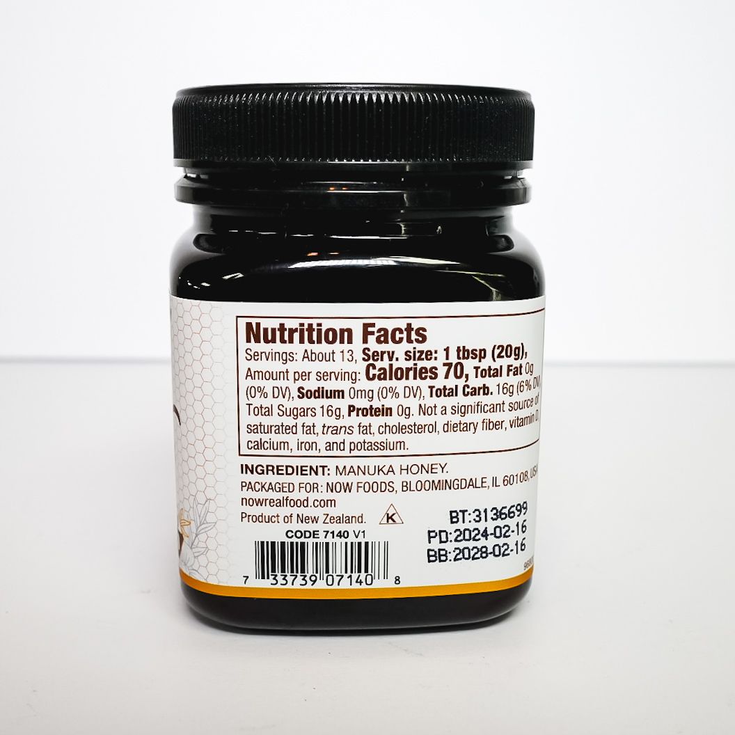 Manuka honey jar with black lid and white label on a light background