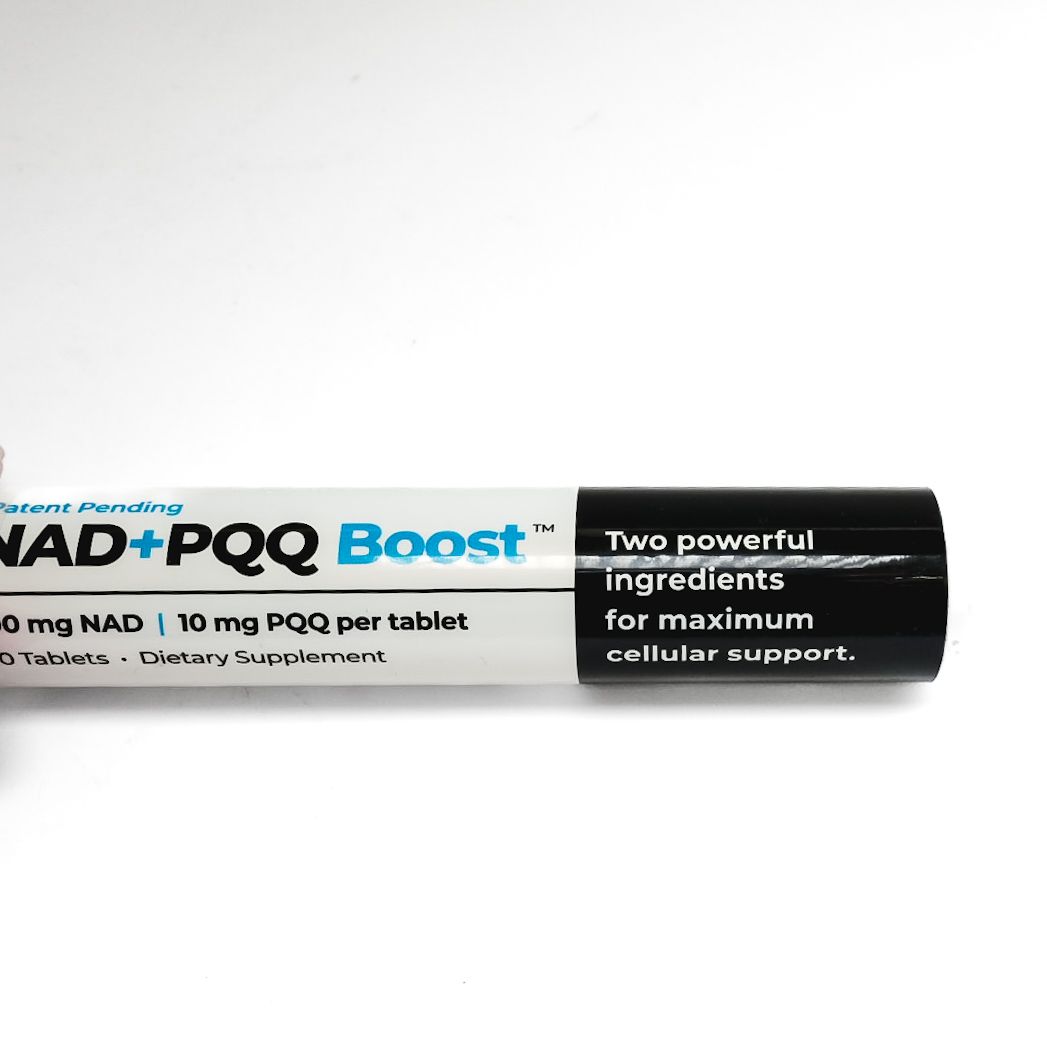 NAD+ Poo Boost lip balm tube, white and black packaging, lying horizontally on a white background