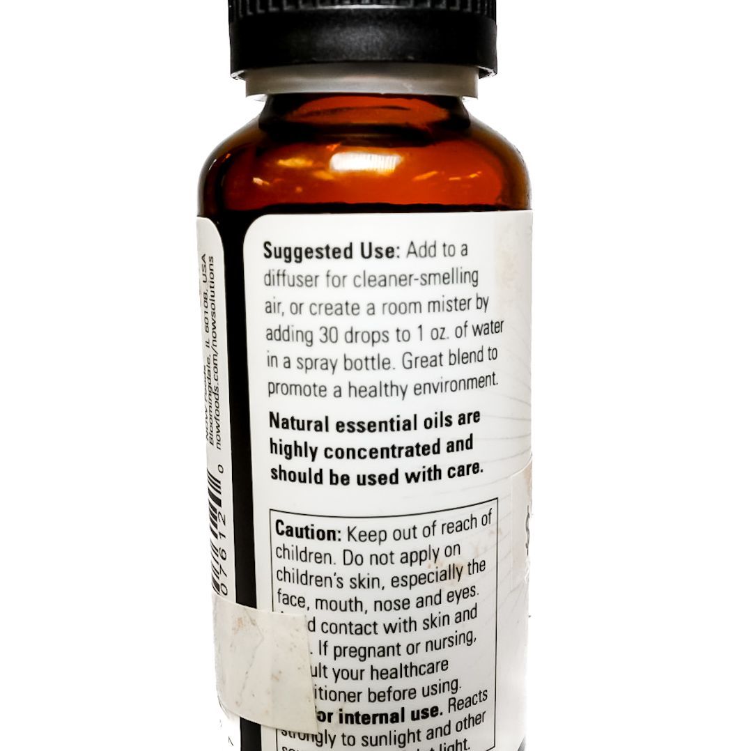 Small amber essential oil bottle with black cap and green leaf label on a white background