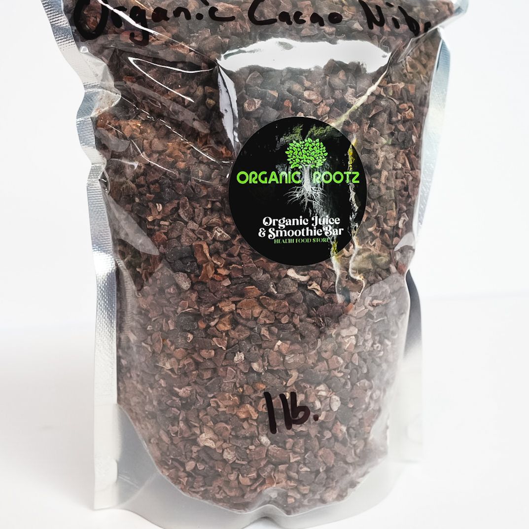 Clear plastic bag of dark roasted coffee beans with a black and green label on a white background
