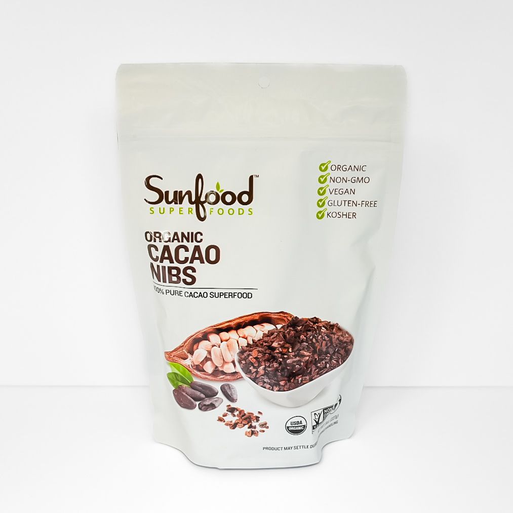 Sunfood cacao nibs bag with bowl of cacao nibs on white background