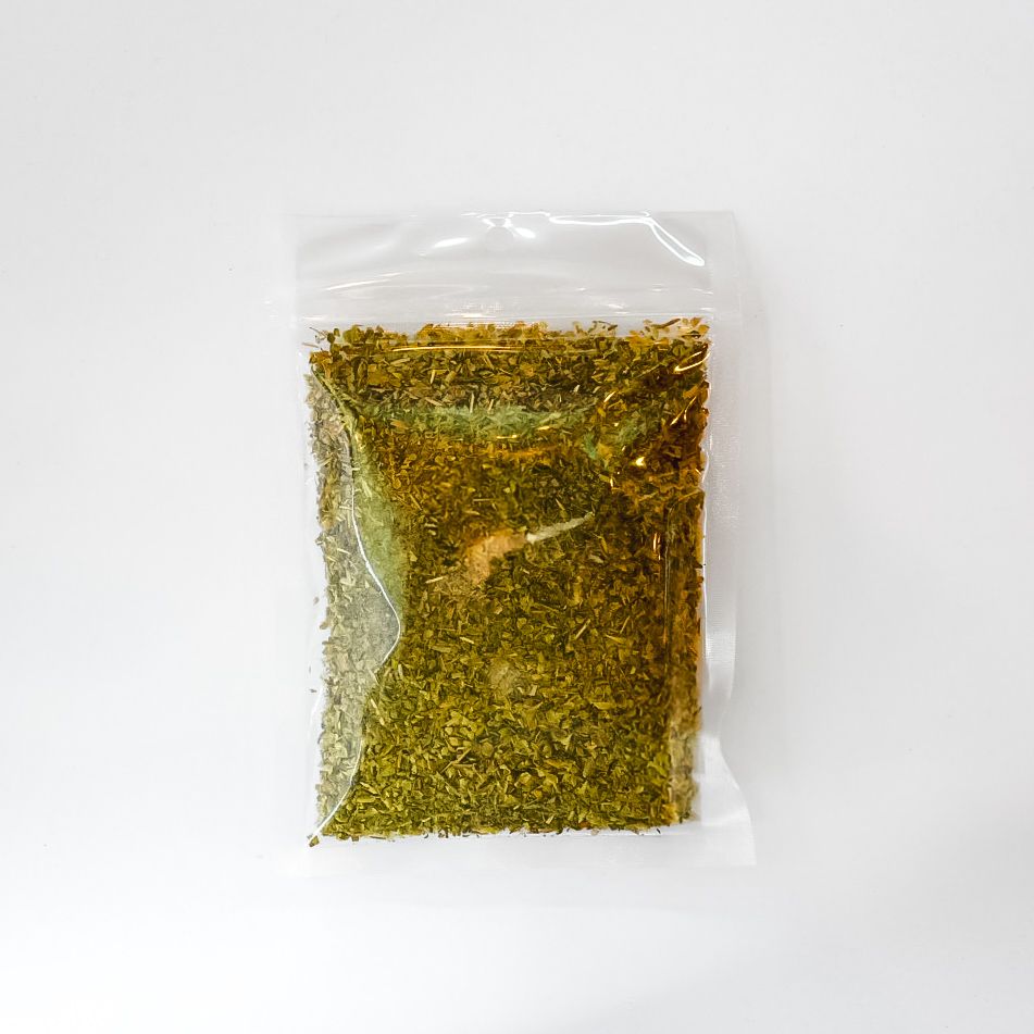 Clear plastic bag of dried oregano leaves with a bright yellow label on a white background
