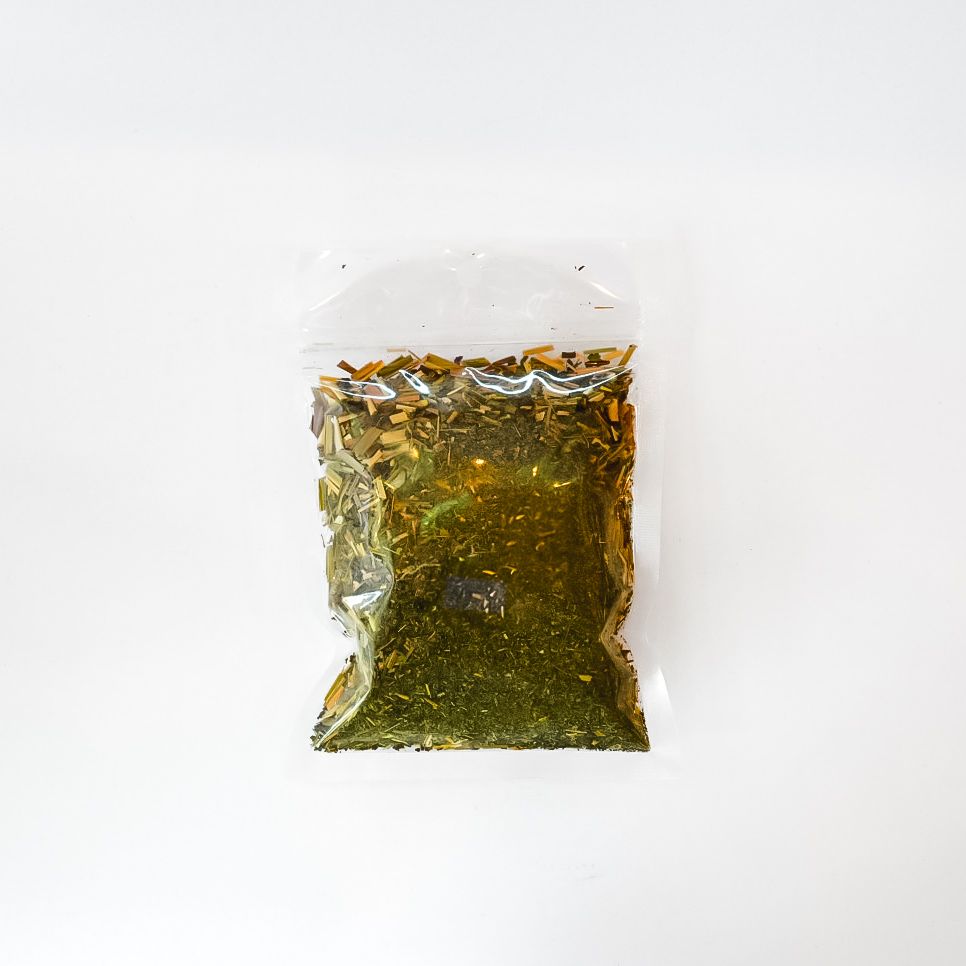 Clear plastic bag of dried herbs or tea with a bright yellow label on a white background