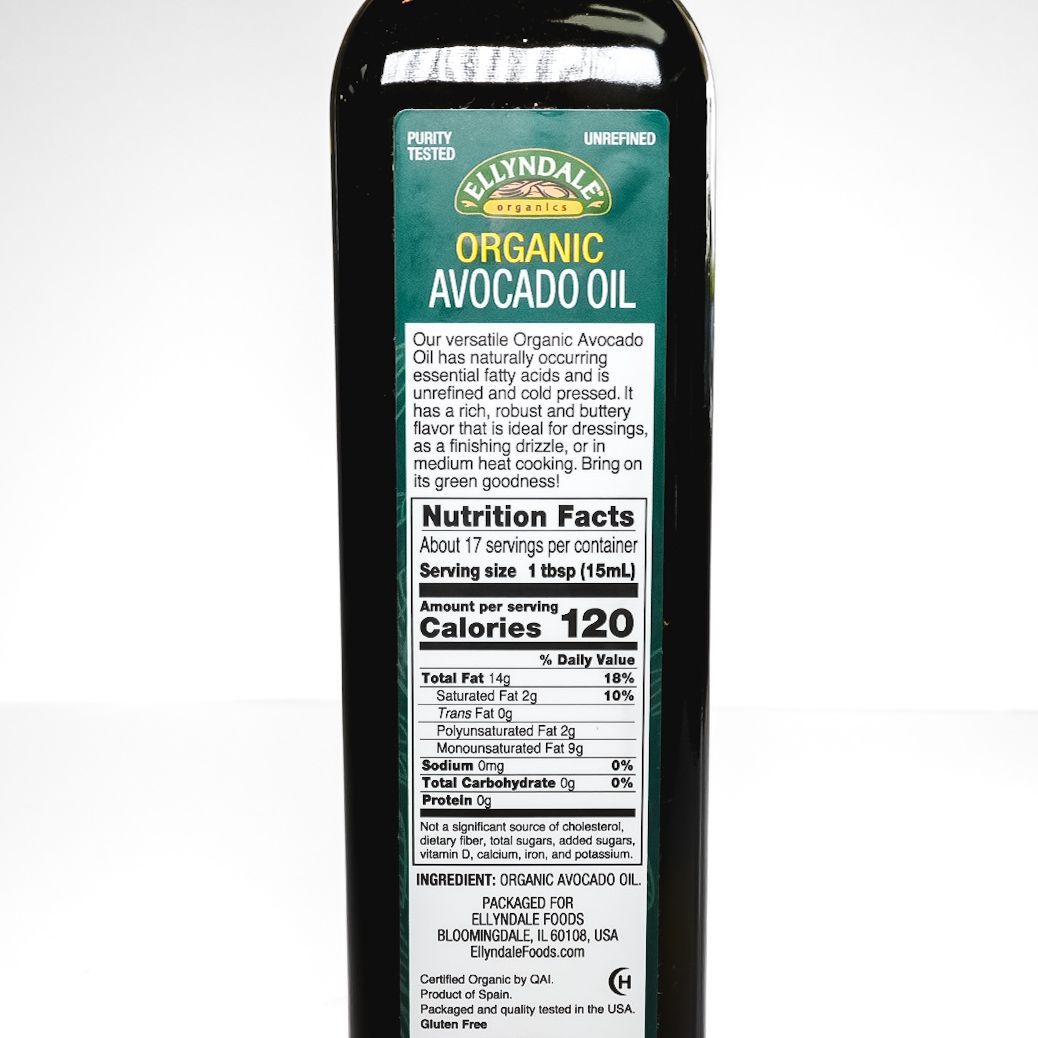 Bottle of organic avocado oil with green label and black cap on a white background