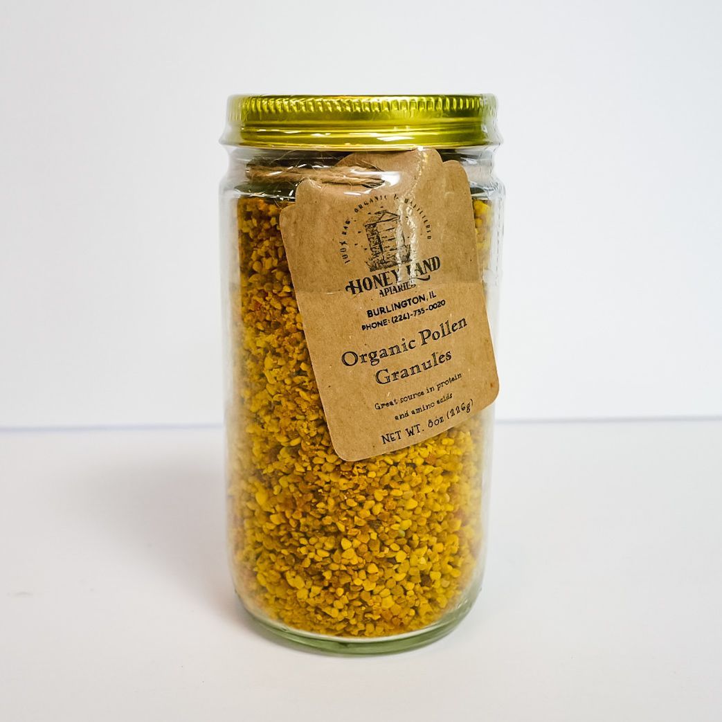 Glass jar of yellow granules with a gold lid and a hanging label on a white background