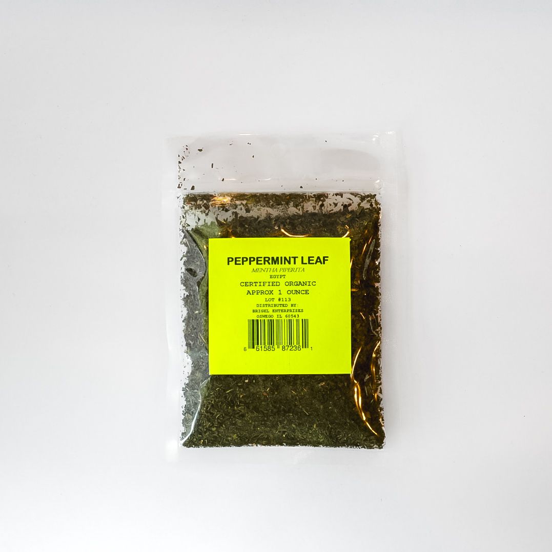 Small clear plastic bag of peppermint leaf tea with a bright yellow label on a white background