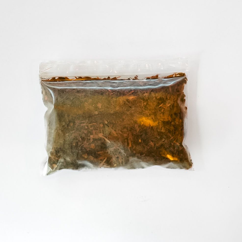 Plastic bag of dried herbs with a bright yellow label on a white background