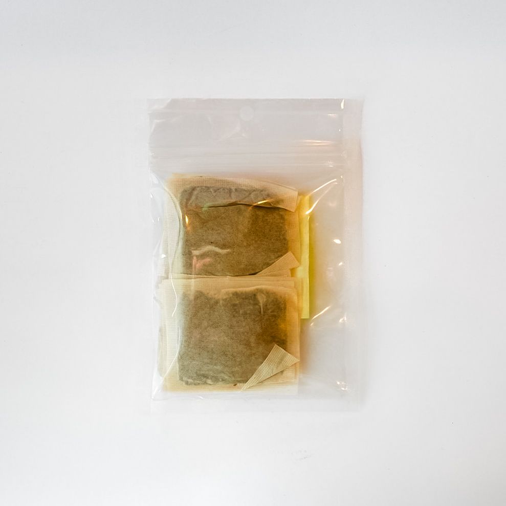 Small clear plastic bag with a bright yellow label containing brown food or spice powder.