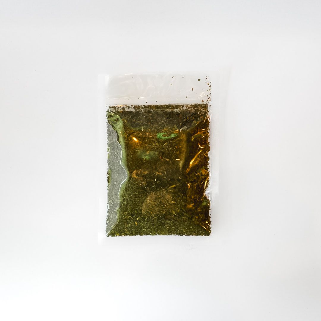 Small clear plastic bag of peppermint leaf tea with a bright yellow label on a white background