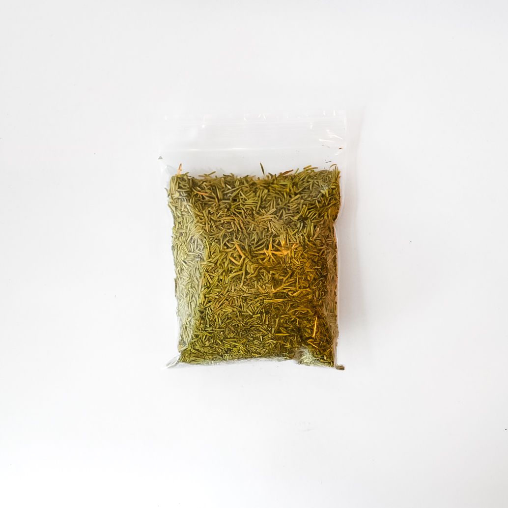 Small clear bag of dried rosemary leaves with a bright yellow label on a white background