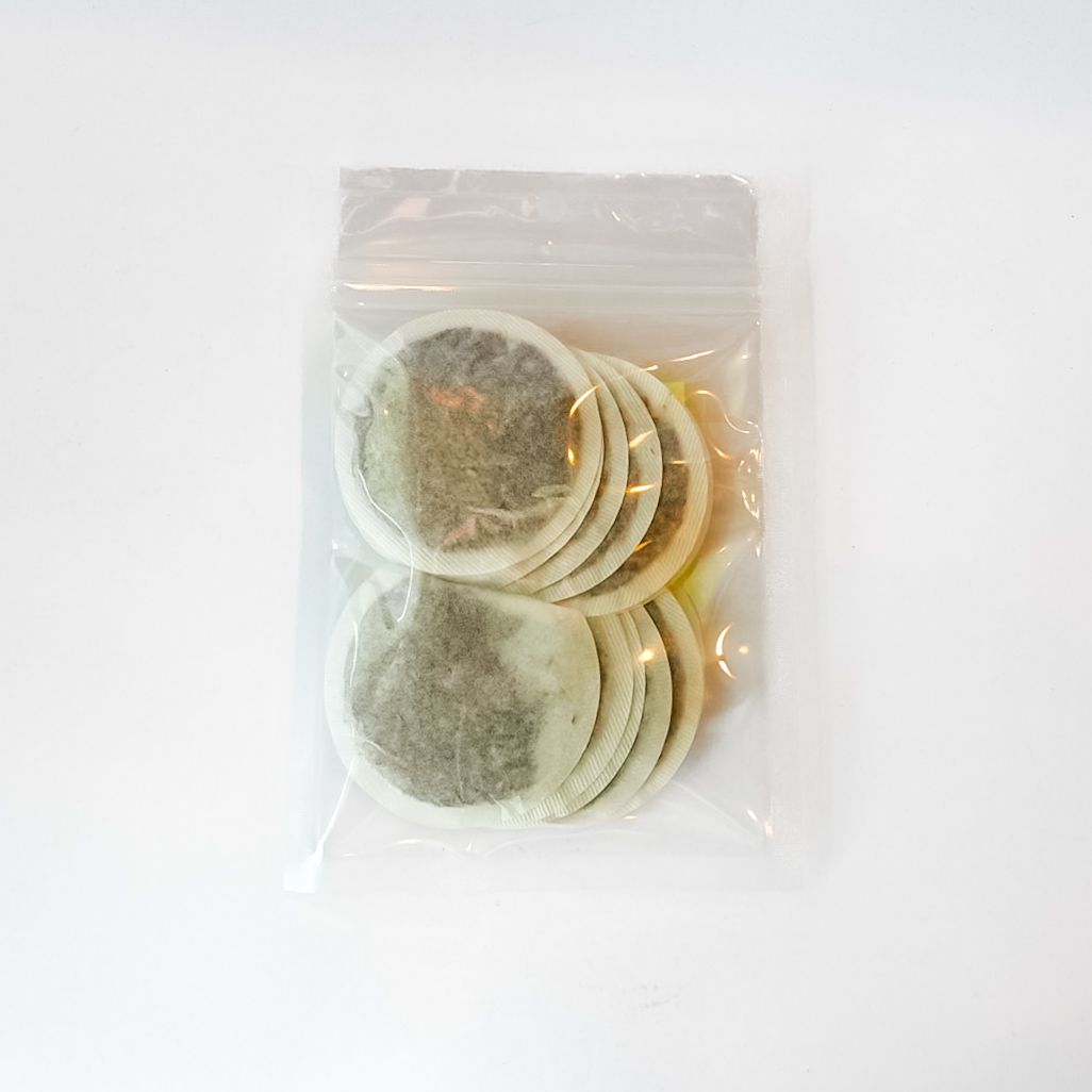 Clear bag of assorted tea bags with a bright yellow label on a white background