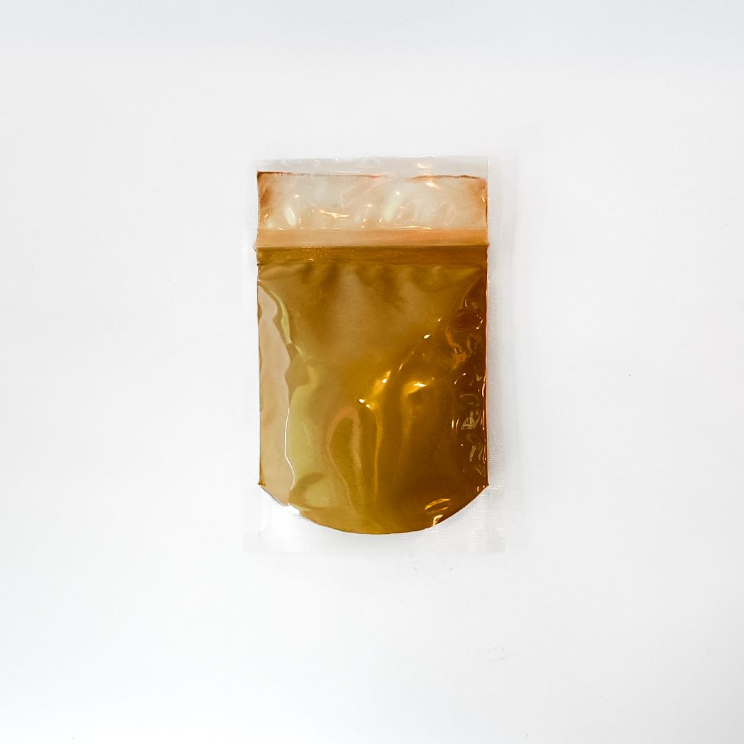 Small clear pouch of yellow-brown root powder with a bright green label and barcode on a white background